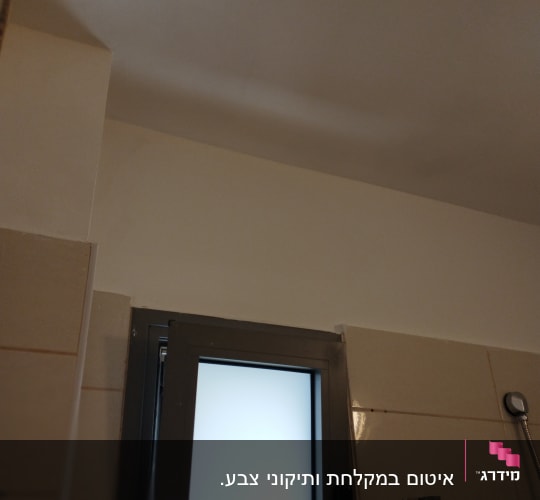 קיר צבוע בלבן ליד חלון עם מסגרת מתכת